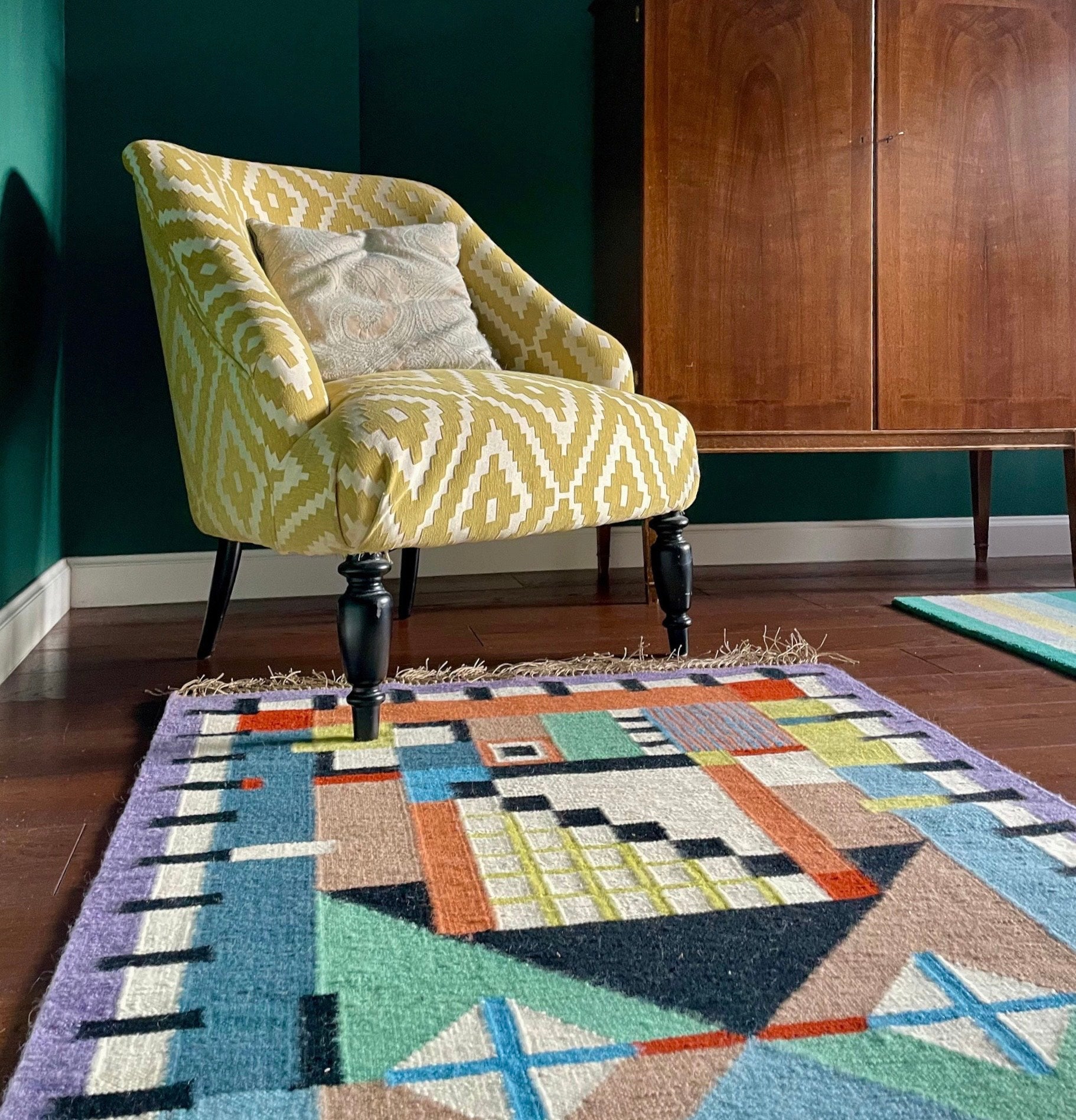 Yellow patterned armchair in a room with a geometric rug on the floor. Rug designed by Piotr Niklas for Splot via Ad Origine.